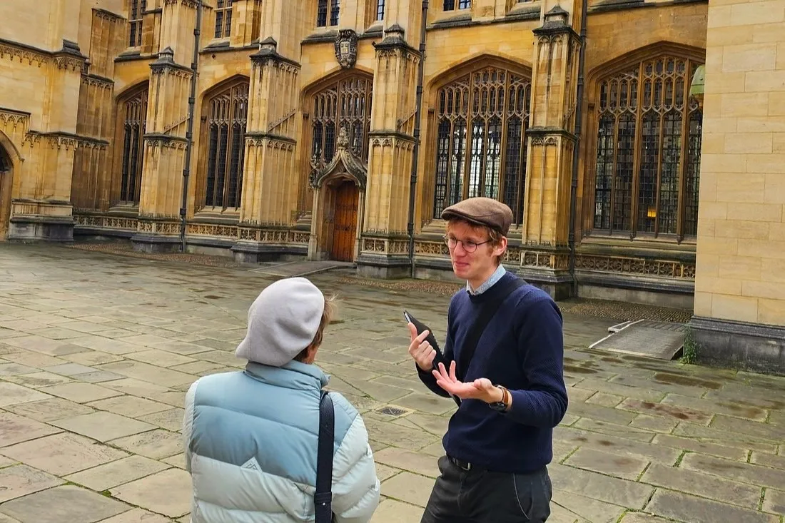 Rory, the tour guide, explains the history of the Divnity School, Oxford, to a visitor.